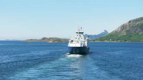 Drone orbit back of Norway ferry with pointed arctic mountain in background