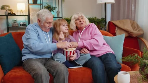 Grandparents and Grandchild Watching TV on Couch