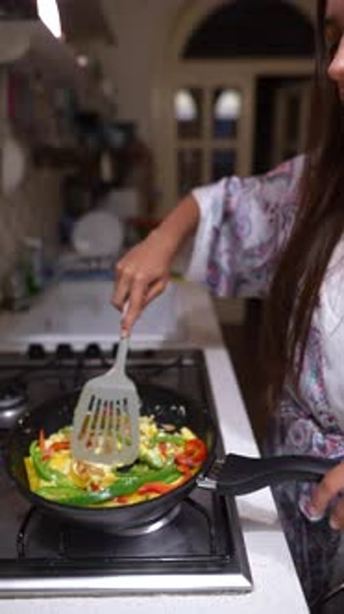 Woman Smiling and Cooking Vegetables in Kitchen