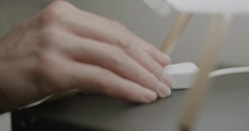 Nahaufnahme einer weiblichen Hand, die das Licht ausschaltet, den Lampenschalter am Nachttisch berührt und nachts schläft