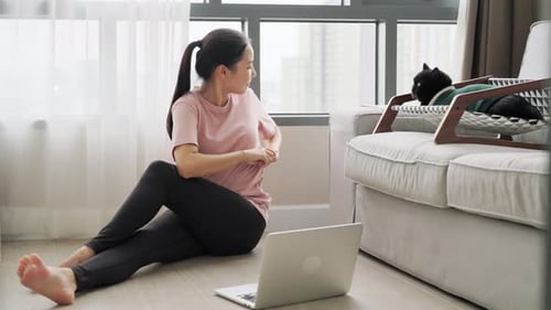 4K Молодая азиатская женщина учится упражнению, просматривая онлайн-уроки на ноутбуке в гостиной