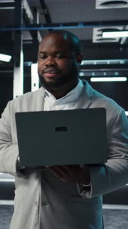 Vertical Video Data Center Engineer Coding on Laptop Doing Software Updates for Mainframes