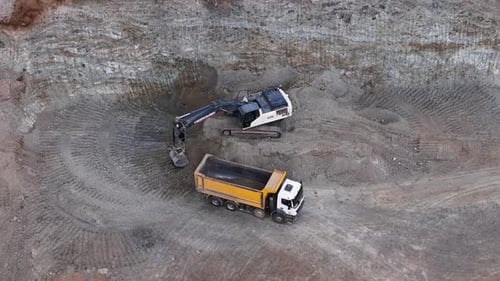 Excavator Loading Dump Truck in Construction Site Aerial