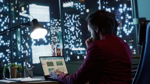 Adult Working on Laptop at Desk at Night