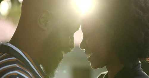 Romantic African black couple together in union outside with lens-flare
