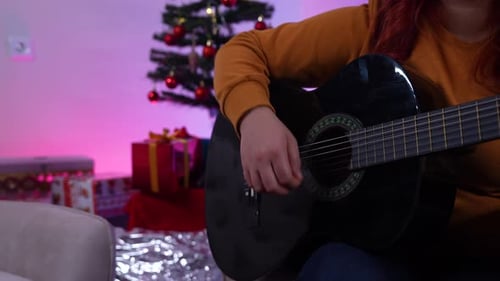 Woman Playing Guitar at Christmas Indoors