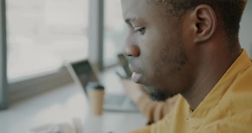 Tiltdown Portrait of Young Successfun AfroAmerican Businessman Working with Laptop in Shared Office