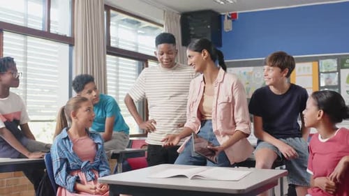 In school, teacher using tablet and interacting with students in classroom