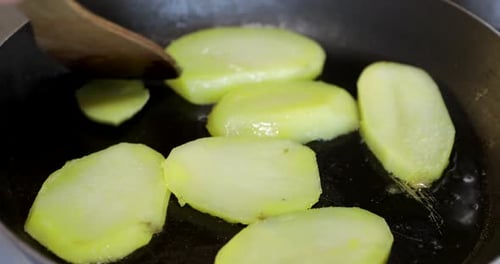 Sauteing Thickly Sliced Raw Potatoes in Hot Oil for Crispy Texture