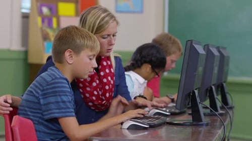 Teacher Helping Students with Computers in Classroom