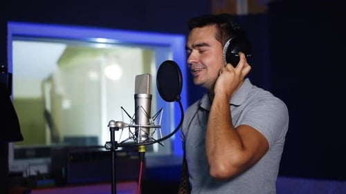 Male singer performing his song emotionally in studio.