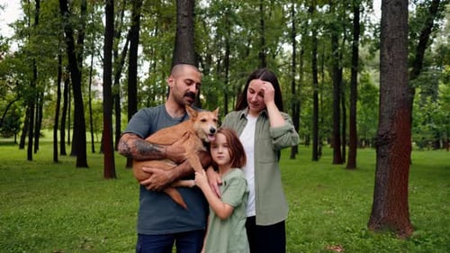 portrait of happy young family in park with dog dad mom daughter resting concept of trust care