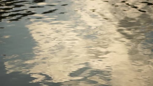 Ripples on Water Surface with the Reflection of Sky and Clouds Clouds in Blue Sky Reflect on Lake