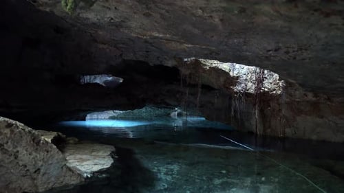 Tilt up shot of a beautiful underground Mexican Cenote with lights shining in from above and crystal