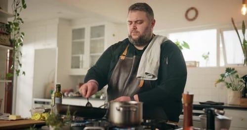Man Cooking in Kitchen Stirring Food in Pan
