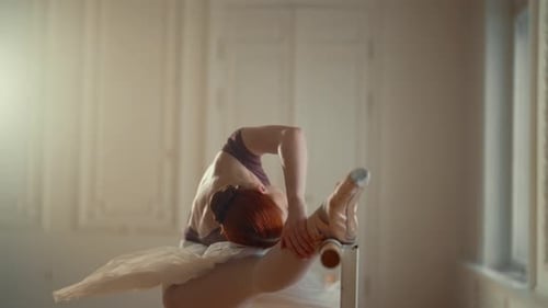 Graceful Ballerina Stretching at the Barre in Studio