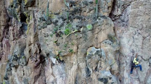 Climber Ascends Rocky Mountain on Sunny Day