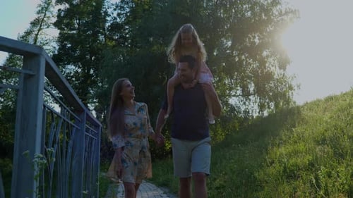 Caucasian Family with a Kid Walking Outdoor in Park on Sunny Summer Day