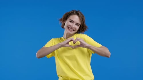 Woman Making Heart Shape Against Blue Background