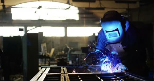 .A blacksmith or welder, with his welder, welding steel and iron, in extreme slow motion. The weld