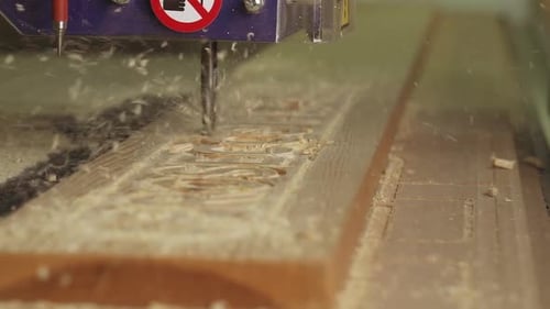 Eine Nahaufnahme in Zeitlupe einer CNC-Maschine, die ein Holzschild schneidet.