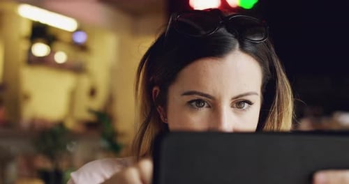4k video footage of an unrecognisable woman sitting alone in a cafe and using a digital tablet