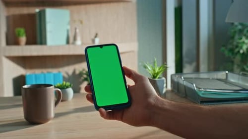 Unrecognizable Man Holding Greenscreen Smartphone at Agency Workplace Close Up