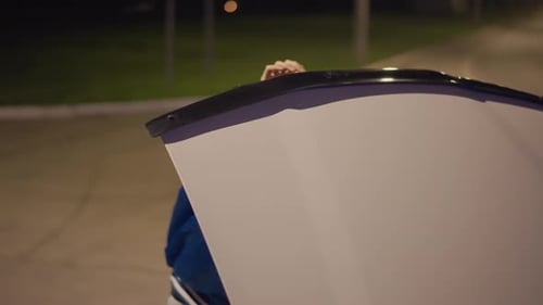 Night Curbside White Driver Peers Over Hood Inspecting Engine Blue Jacket Focused Profile Quiet