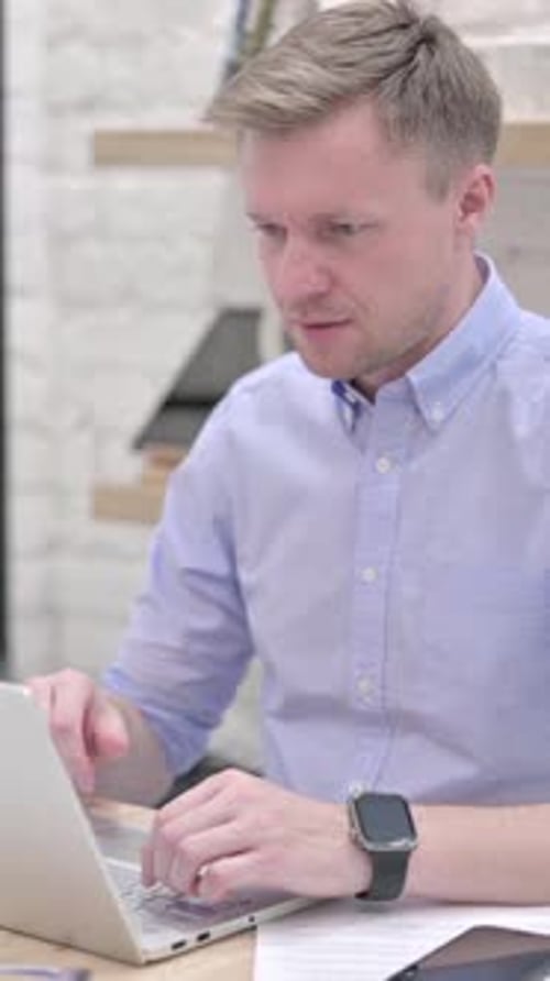 Man Working at Laptop Rejoices in Office