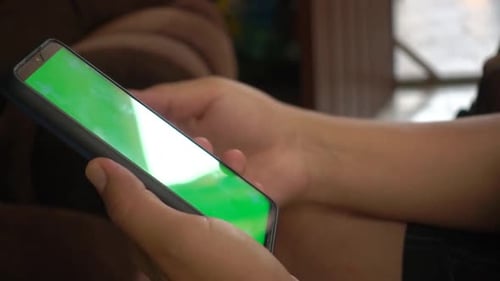 Lateral view of hands taping on an smartphone chroma screen.