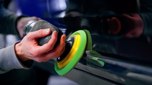 Closeup of the Hands of a Car Mechanic at a Service Station Doing the Final Polishing to Shine