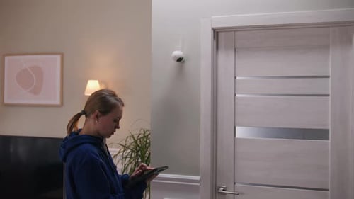 Frau richtet Sicherheitskamera mit Tablet ein