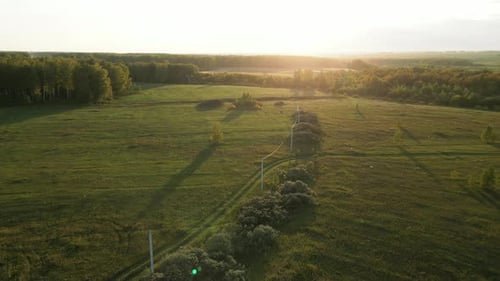Luftaufnahme von Hochspannungsmasten auf dem Feld am Abend vor Sonnenuntergang