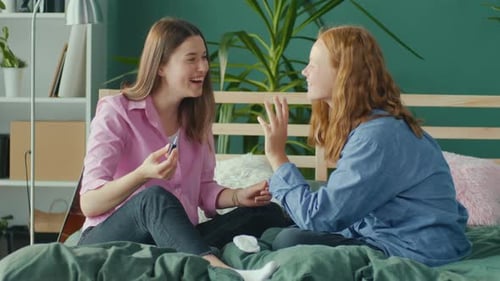 Girlfriends Students Sit at Home on Bed and Paint Nails Two Sisters Having Fun