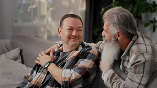 Happy Elderly Man with Gray Hair and a Lush Beard Communicates and Hugs His Brunette Boyfriend with
