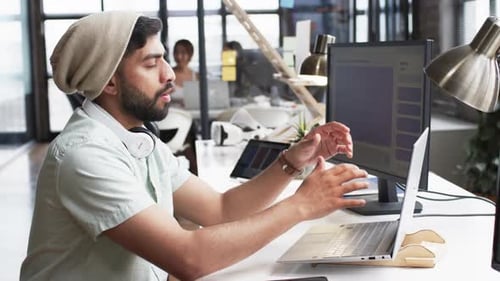 Young Asian man in a business office setting, focused on his computer screen