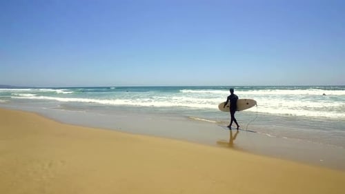 Surfer Walks with Surfboard on Beach by the Ocean Active Couple