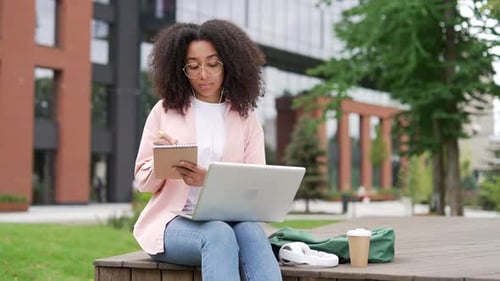 Young Woman Studying with Laptop and Notebook