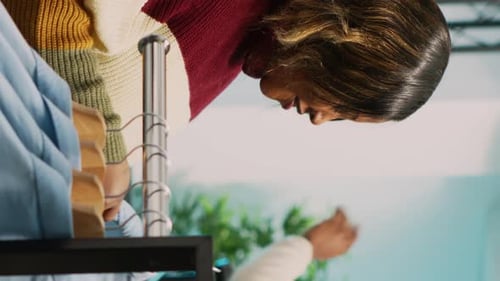 Vertical Video Asian Employee Showing Clothes to Customer in Retail Shop