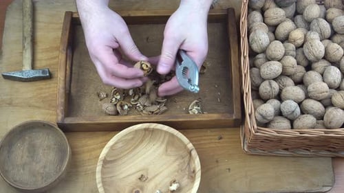Male Hands Clean Nuts with a Nut Cracker Closeup Walnut in Shell Top View