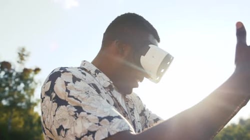 Amazed Smiling AfroAmerican Man Takes Off Glasses of Virtual Reality on a Bright Sunlight