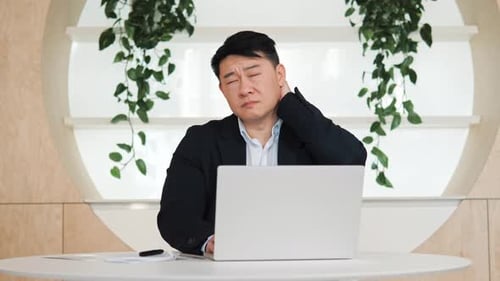 Man Massages Stiff Neck at Workplace