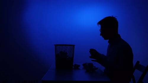 Silhouette man at desk throws crumpled paper into trash