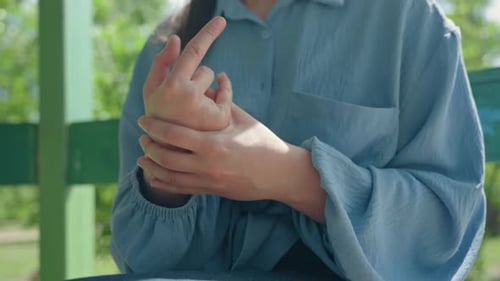 Woman Massaging Her Sore Wrists Outdoors