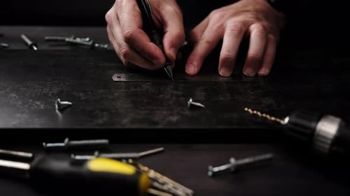 Carpenter is Marking a Board for Drilling