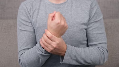 Man Massaging Sore Wrist in a Home