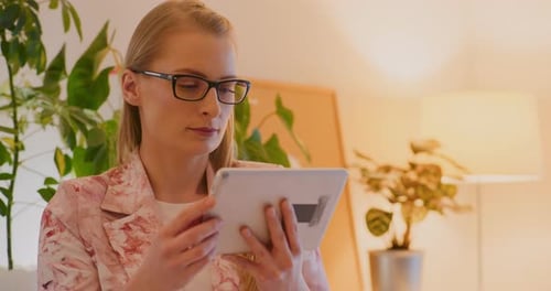 Woman Using Tablet Indoors Surrounded by Plants
