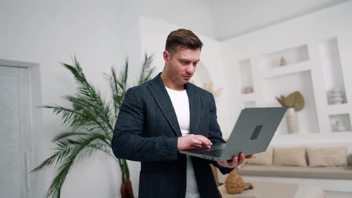 Smiling Man in Blazer Using Laptop Indoors