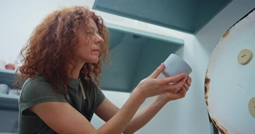 Woman Holding Ceramic Cup in Pottery Studio