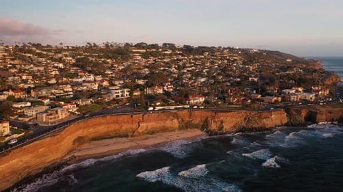 Aerial pan at sunset of waves and bluffs and homes on Sunset Cliffs in San Diego